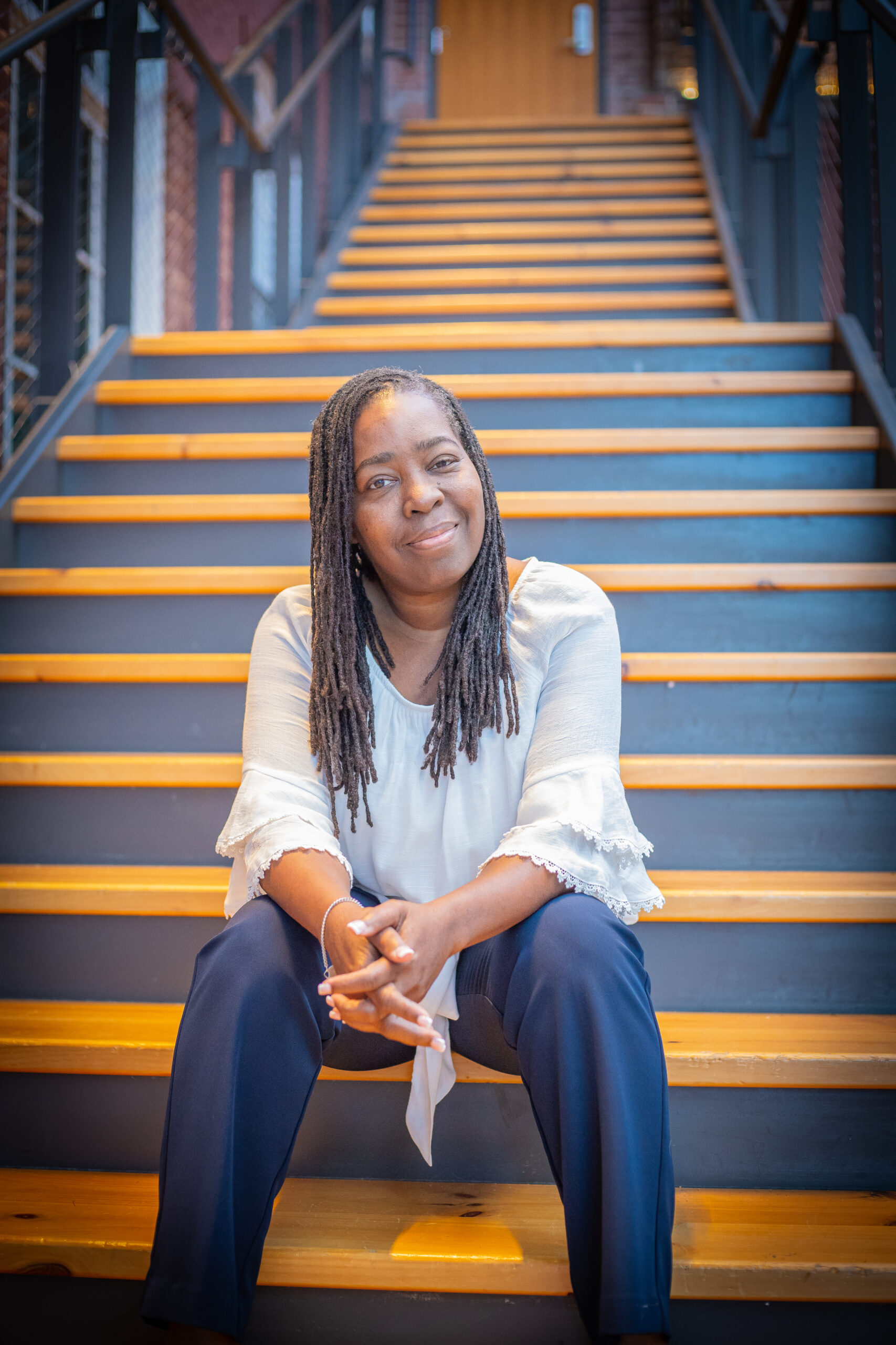 Photo of Dr. Michelle Watson-Grant, Founder of Jonlieu, sitting at the base of a staircase