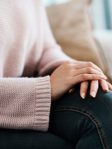 Woman sitting with hands resting on her knee in a calm, composed manner