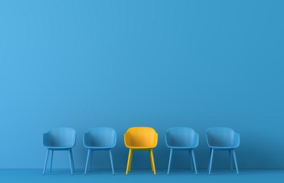 Yellow chair stands out among four blue chairs